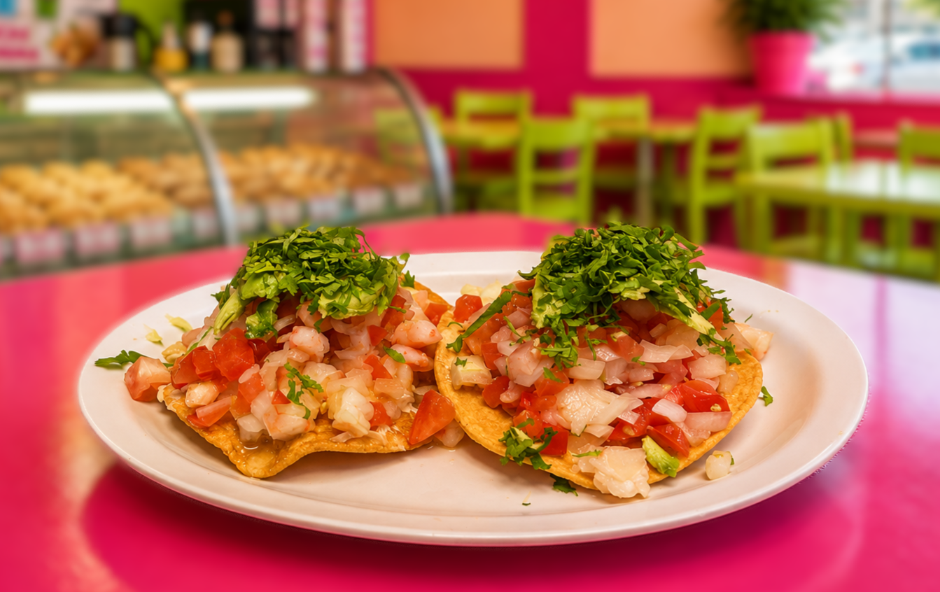 Two shrimp tostadas topped with pico de gallo, avocado, and cilantro